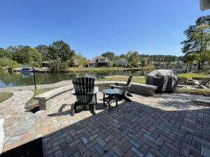 A paver patio outside of a home overlooks a lake.