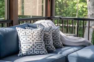 Close up of blue patio furniture in modern screened porch, summertime woods in the background.