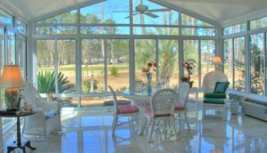 The interior of a large sunroom has large glass walls and a vaulted ceiling.